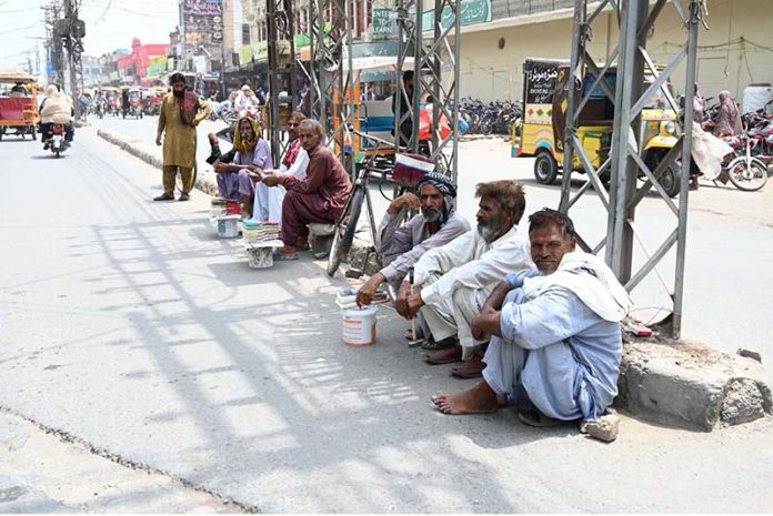 Workers sitting on the roadside at Gol Chowk wait for potential customers to hire them for daily labor work