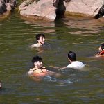 People cool off in the stream at Angoori Dam to escape the sweltering heat in the federal capital