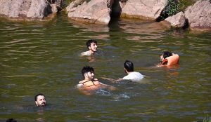 People cool off in the stream at Angoori Dam to escape the sweltering heat in the federal capital