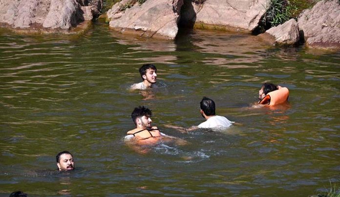 People cool off in the stream at Angoori Dam to escape the sweltering heat in the federal capital