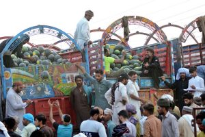 A vendor arranges watermelons to attract customers at a fruit market.