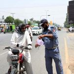 A traffic policeman is providing water to citizens at Club Chowk in the scorching heat