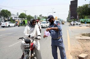 A traffic policeman is providing water to citizens at Club Chowk in the scorching heat
