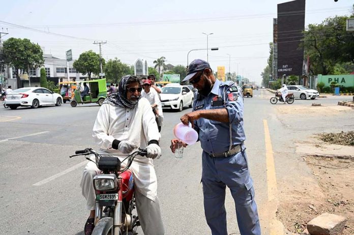 A traffic policeman is providing water to citizens at Club Chowk in the scorching heat