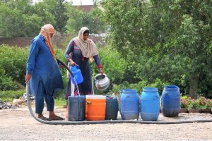 Gypsy family filling their pots with clean drinking water at a roadside.
