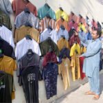 Vendor selling and displaying T-shirts to attract the customers at his roadside setup