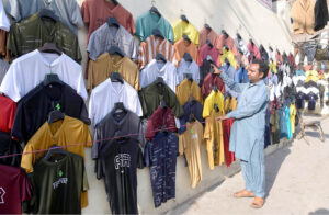 Vendor selling and displaying T-shirts to attract the customers at his roadside setup