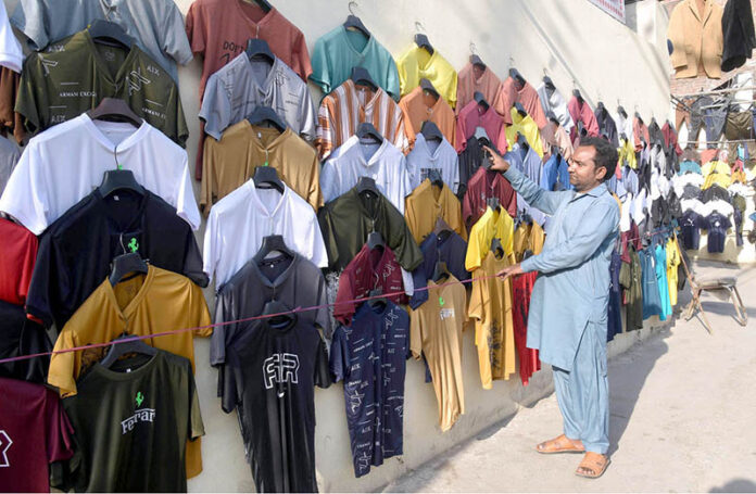 Vendor selling and displaying T-shirts to attract the customers at his roadside setup