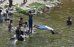 A youngster dives into the Korang Nullah near Rawal Dam to swim and cool off during warm weather in the federal capital