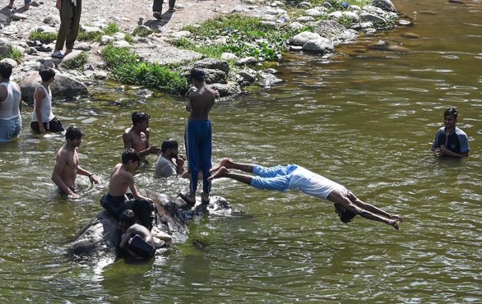 A youngster dives into the Korang Nullah near Rawal Dam to swim and cool off during warm weather in the federal capital
