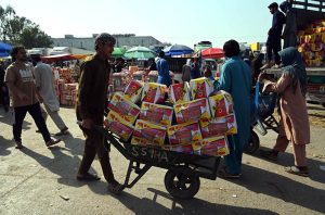 A laborer pushes a wheelbarrow loaded with fruit crates to deliver them from a delivery truck to stalls at the Fruit and Vegetable Market in the Federal Capital.