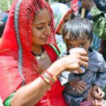 A woman gives her child summer drink at a heatstroke relief camp during hot weather in the city