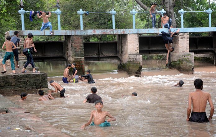 To escape the heat and humidity, people dive, swim, and bathe in the Lahore Canal, seeking relief from the sweltering weather in the city