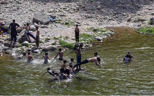 A youngster dives into the Korang Nullah near Rawal Dam to swim and cool off during warm weather in the federal capital