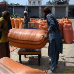 Laborers weigh sacks of dry fodder chuff for cattle before selling in the Chamkani area, with increased demand as Eid ul Azha approaches