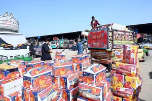 A laborer pushes a wheelbarrow loaded with fruit crates to deliver them from a delivery truck to stalls at the Fruit and Vegetable Market in the Federal Capital.