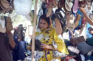 Woman selects and purchase sandals on roadside stall in the City.