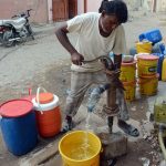 A man uses a hand pump to fill his pots with water in the Korangi area as the city metropolitan suffers from a water shortage