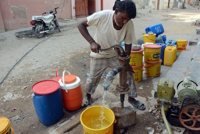 A man uses a hand pump to fill his pots with water in the Korangi area as the city metropolitan suffers from a water shortage