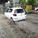 A vehicles passes through stagnant rainwater, causing inconvenience for commuters on Saddar Road