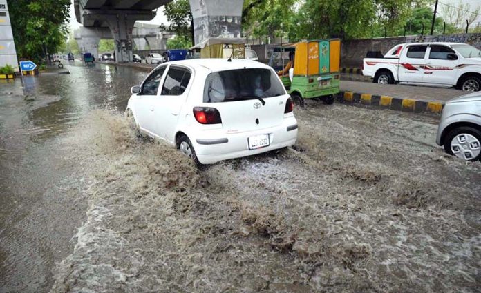 A vehicles passes through stagnant rainwater, causing inconvenience for commuters on Saddar Road
