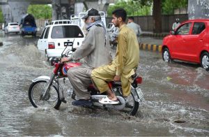 A vehicles passes through stagnant rainwater, causing inconvenience for commuters on Saddar Road