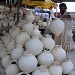 A man sells traditional clay water pitchers used to keep water cool, amid rising demand due to high temperatures