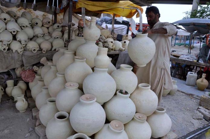 A man sells traditional clay water pitchers used to keep water cool, amid rising demand due to high temperatures