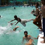 Youths dive into a swimming pool to beat the intense heat in Village Chooharpur near Larkana