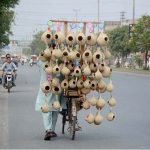 A street vendor displays crafted artificial bird nests for garden décor to attract customers on his bicycle in the local market