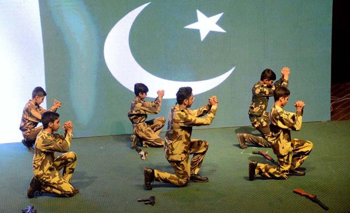 Students performing a patriotic tableau on the stage during Express Solidarity with Pakistan Armed Forces following the successful military operation Bunyanun Marsoos against Indian Aggressions