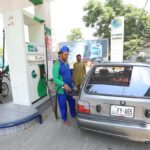 Petrol pump workers fill fuel into customers' vehicles as the government announces a 2-rupee reduction in petrol prices