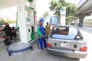 Petrol pump workers fill fuel into customers' vehicles as the government announces a 2-rupee reduction in petrol prices