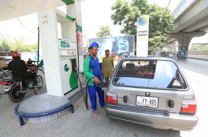 Petrol pump workers fill fuel into customers' vehicles as the government announces a 2-rupee reduction in petrol prices