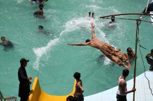 Youths dive into a swimming pool to beat the intense heat in Village Chooharpur near Larkana