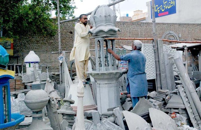 An artist works on crafting a mosque minaret at a local factory
