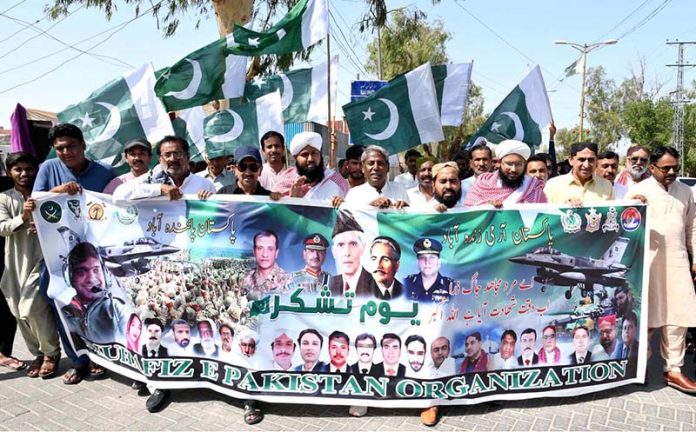 Workers of Muhafiz Pakistan Organization hold national flags as they march during a rally to express solidarity with Pakistan's armed forces at SSP Office Chowk