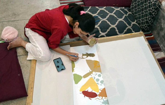 A student engages in painting and drawing activities during an art class at Alhamra Arts Council