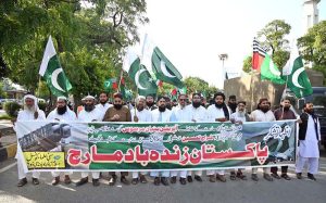 Workers of Muhafiz Pakistan Organization hold national flags as they march during a rally to express solidarity with Pakistan's armed forces at SSP Office Chowk