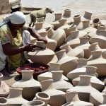 A woman paints traditional clay pots at her workplace, highlighting local craftsmanship