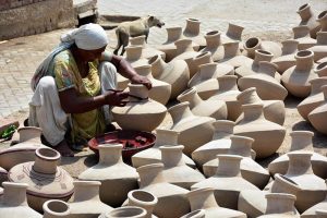 A woman paints traditional clay pots at her workplace, highlighting local craftsmanship