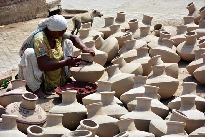 A woman paints traditional clay pots at her workplace, highlighting local craftsmanship