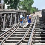 Schoolgirls cross a railway bridge on foot while returning home, reflecting the unsafe and challenging journeys many children endure daily in pursuit of education