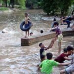 Youngsters enjoying while bathing in water pound to get relief from hot weather in the city