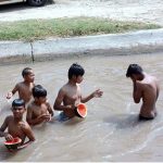 Youngsters eating watermelon during taking bath in a canal in hot day in the city