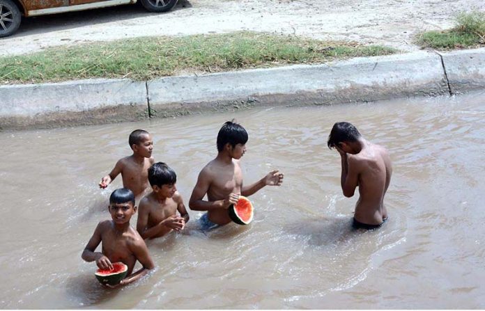 Youngsters eating watermelon during taking bath in a canal in hot day in the city