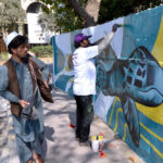 Artist is busy painting a dinosaur picture in different colors on a wall near Liberty Roundabout