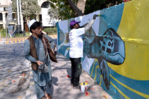 Artist is busy painting a dinosaur picture in different colors on a wall near Liberty Roundabout