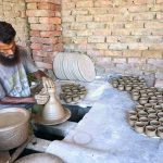 A potter skillfully shapes clay into cups at his workplace