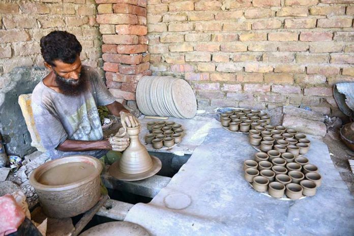 A potter skillfully shapes clay into cups at his workplace